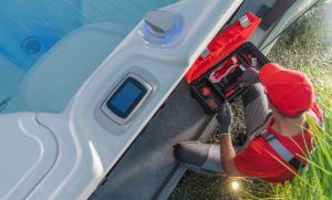 repairman kneeling with tools performing a hot tub electrical safety inspection