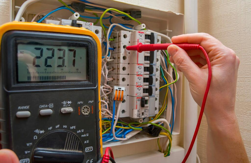 Hand using voltmeter on residential electrical panel