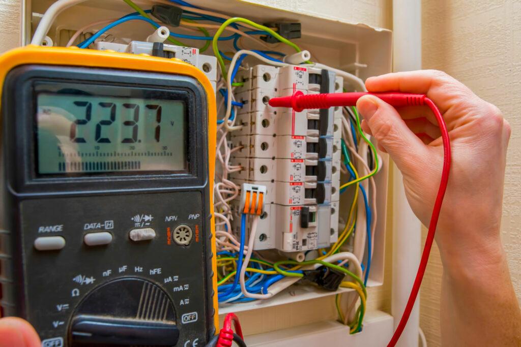 voltmeter and hand holding wand near residential electrical panel 