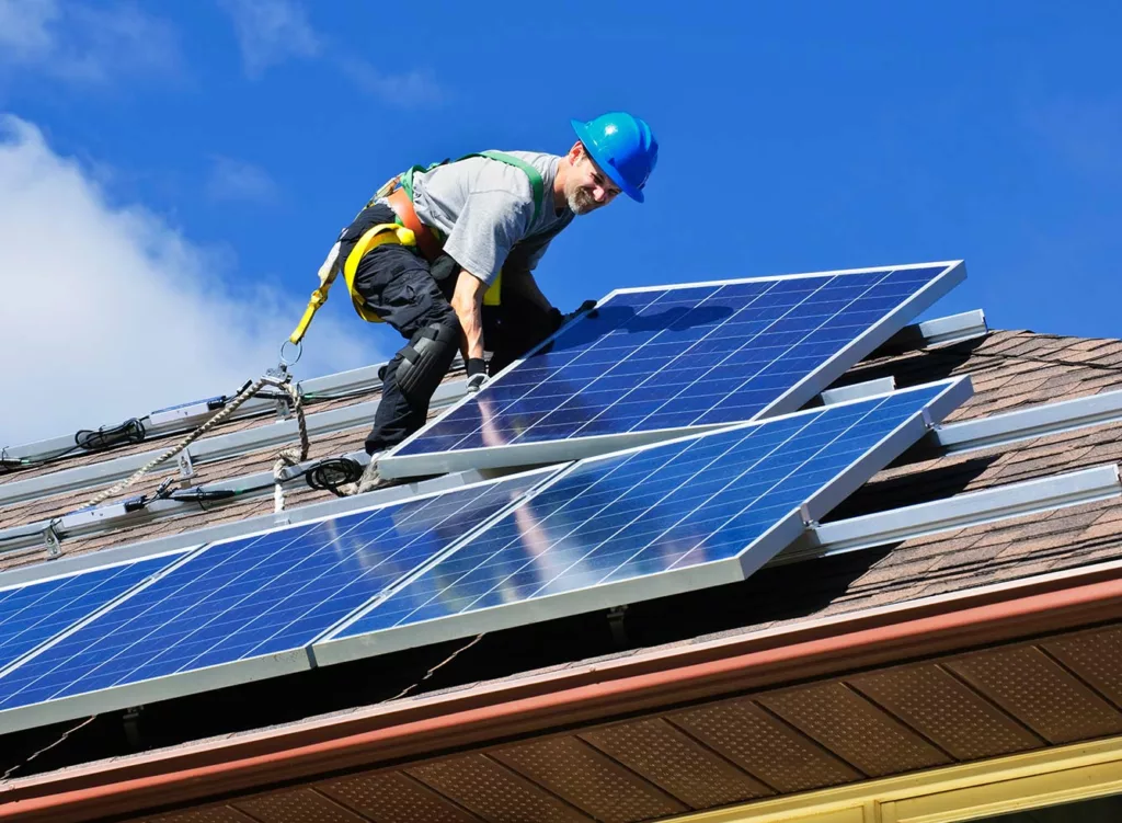 Electrician installing solar panels on the roof of a house.