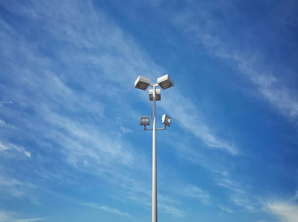 A commercial parking lot light against a blue sky.