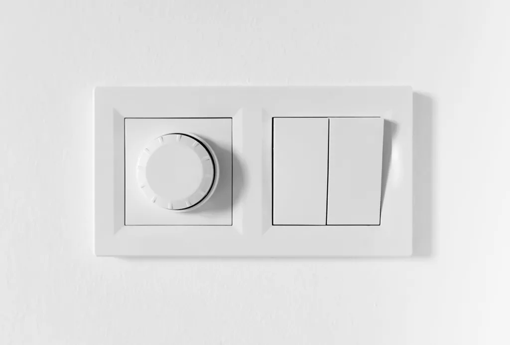 A pair of light switches and a dimmer switch on a white wall