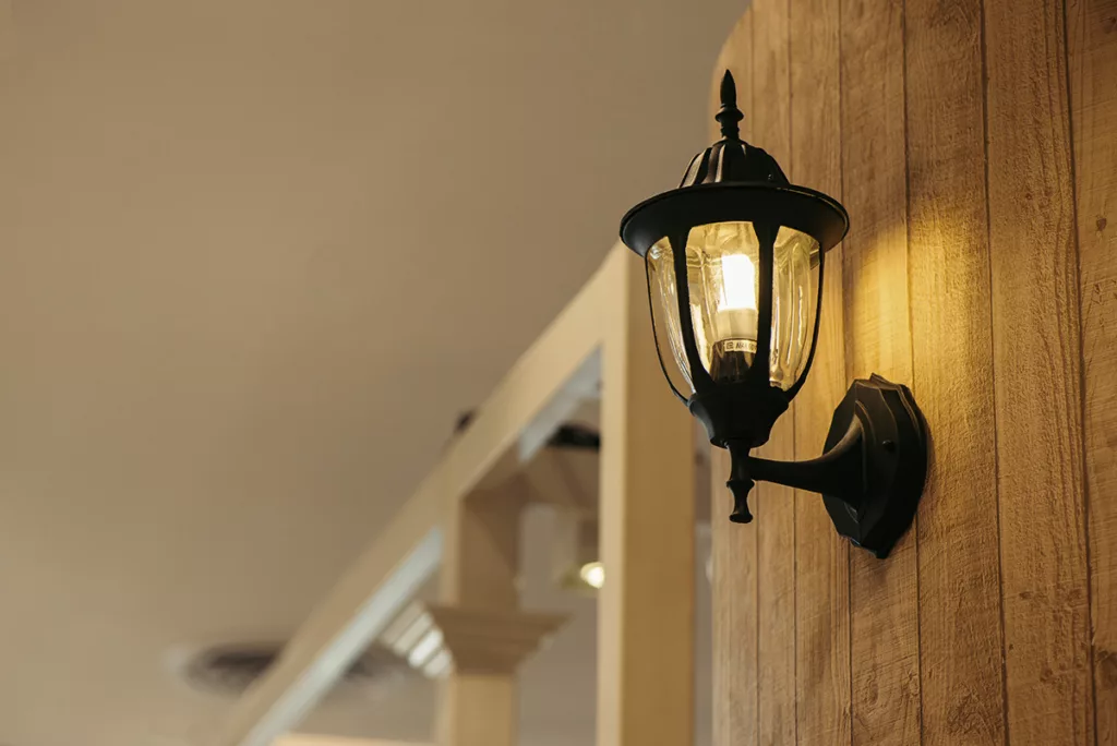 A front porch light against a wood wall, with bright LED lightbulbs