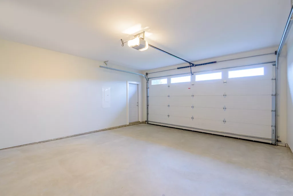 An empty residential garage with white walls and a light on the ceiling with bright LED light bulbs