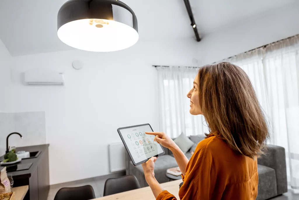 Young woman controlling home LED light with a digital tablet in the living room
