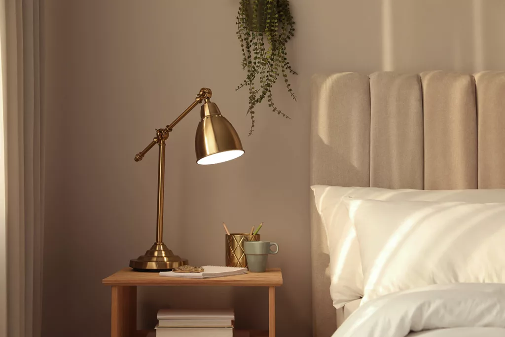 A bedroom with a bed and a nightstand, and a lamp with warm, ambient LED lighting.