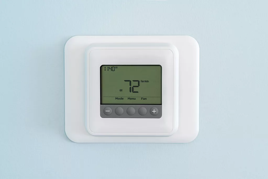 A close up photo of a thermostat on a light blue wall