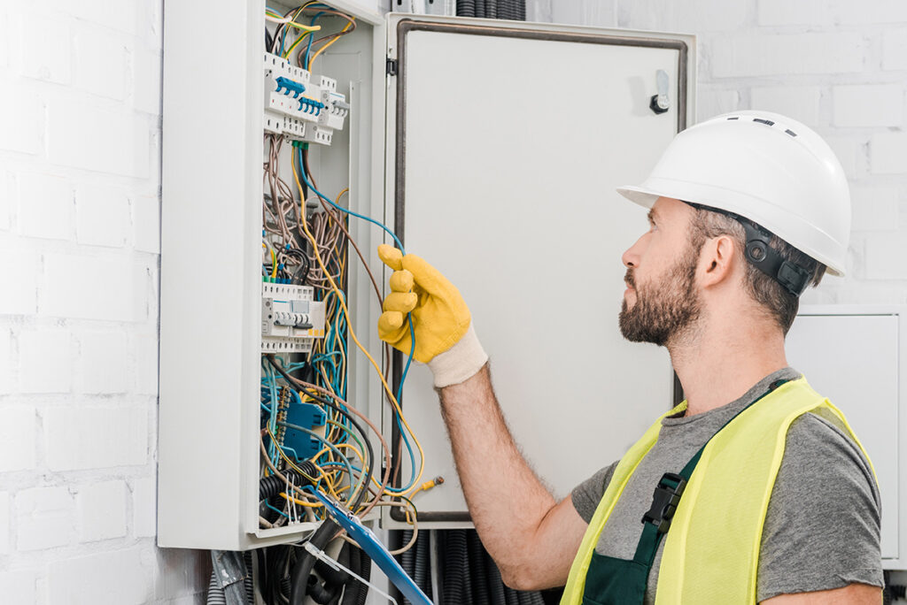 An electrician inspecting the wires in a house with white walls